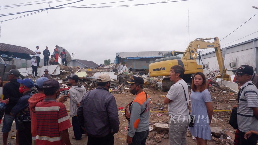Warga menonton aktivitas pembersihan lokasi ambruknya bangunan toko Alfamart di Kecamatan Gambut, Kabupaten Banjar, Kalimantan Selatan, Selasa (19/4/2022).