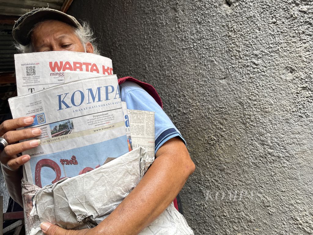 Rahmad (53) berjualan koran dengan berkeliling Pasar Jatinegara, Jakarta Timur, Minggu (10/10/2021). Menurut Rahmad, kini pembeli koran kian sedikit dan pendapatannya turun drastis. 