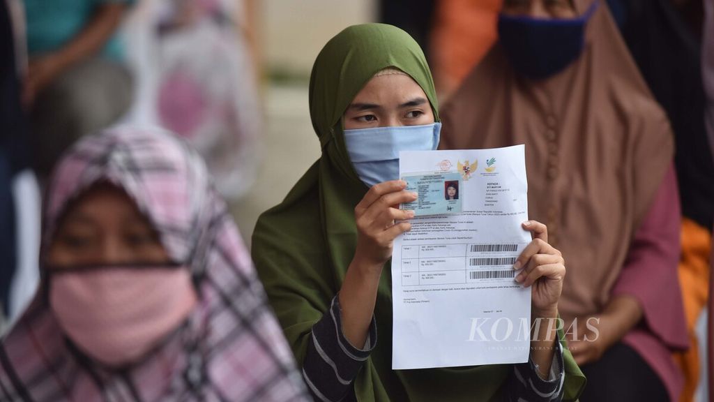 Warga menunjukkan kartu identitasnya saat akan mencairkan Bantuan Sosial (Bansos) Tunai di Kantor Pos Kecamatan Curug, Kabupaten Tangerang, Banten, untuk mencairkan Bansos Tunai, akhir April 2020. 