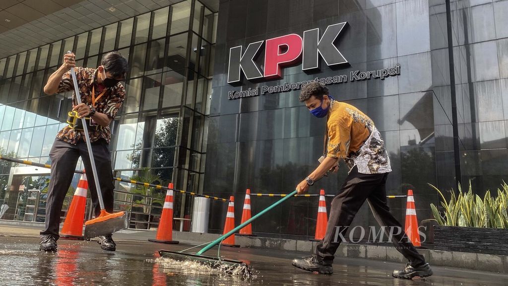 Petugas kebersihan membersihkan jalan masuk ke Gedung Komisi Pemberantasan Korupsi (KPK), Kuningan, Jakarta, dari genangan air hujan, Jumat (22/5/2020).
