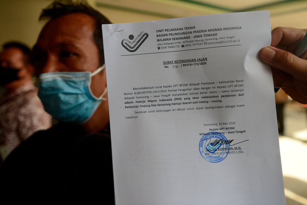 One of the migrant workers from Malaysia shows a travel permit certificate after arriving at Tanjung Emas Port, Semarang City, Central Java, Friday (15/5/2020).  