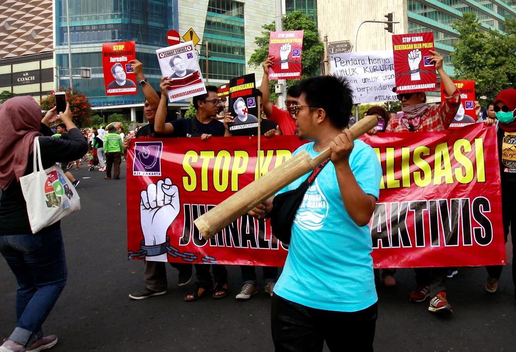 Sejumlah jurnalis memukul kentungan dan melakukan aksi berjalan mundur saat menggelar aksi solidaritas di kawasan Hari Bebas Kendaraan Bermotor, Bundaran Hotel Indonesia, Jakarta, Minggu (29/9/2019). Aksi dilakukan sebagai bentuk protes atas penetapan tersangka terhadap jurnalis sekaligus aktivis Dandhy Dwi Laksono.