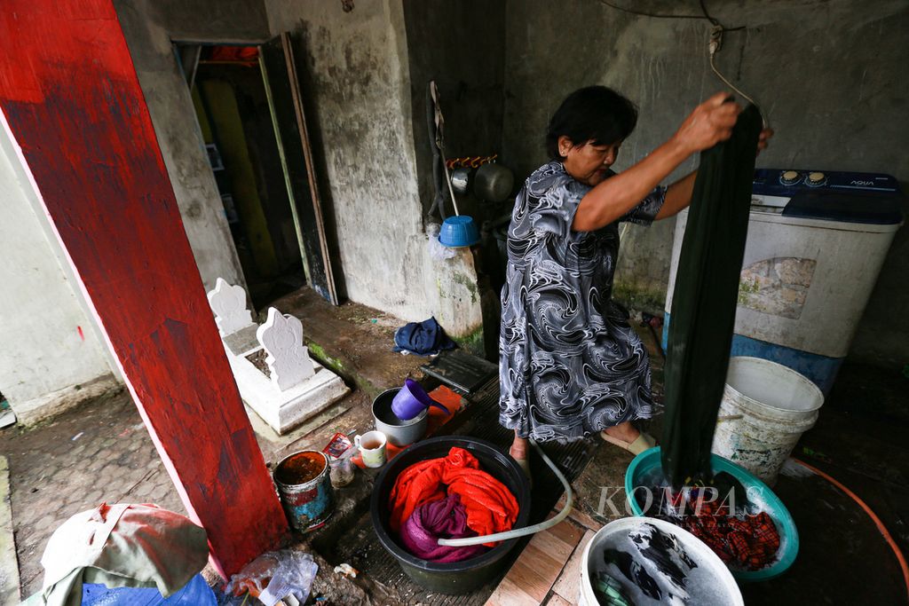 Ida (61) mencuci pakaian di rumahnya yang berada di kompleks TPU Kemlaten, Kecamatan Harjamukti, Kota Cirebon, Jawa Barat, Rabu (23/3/2022). Ia mengakui telah tinggal di rumah yang berdekatan dengan makam sejak tahun 1981. Saat ini terdapat 10 makam di pekarangan rumahnya.