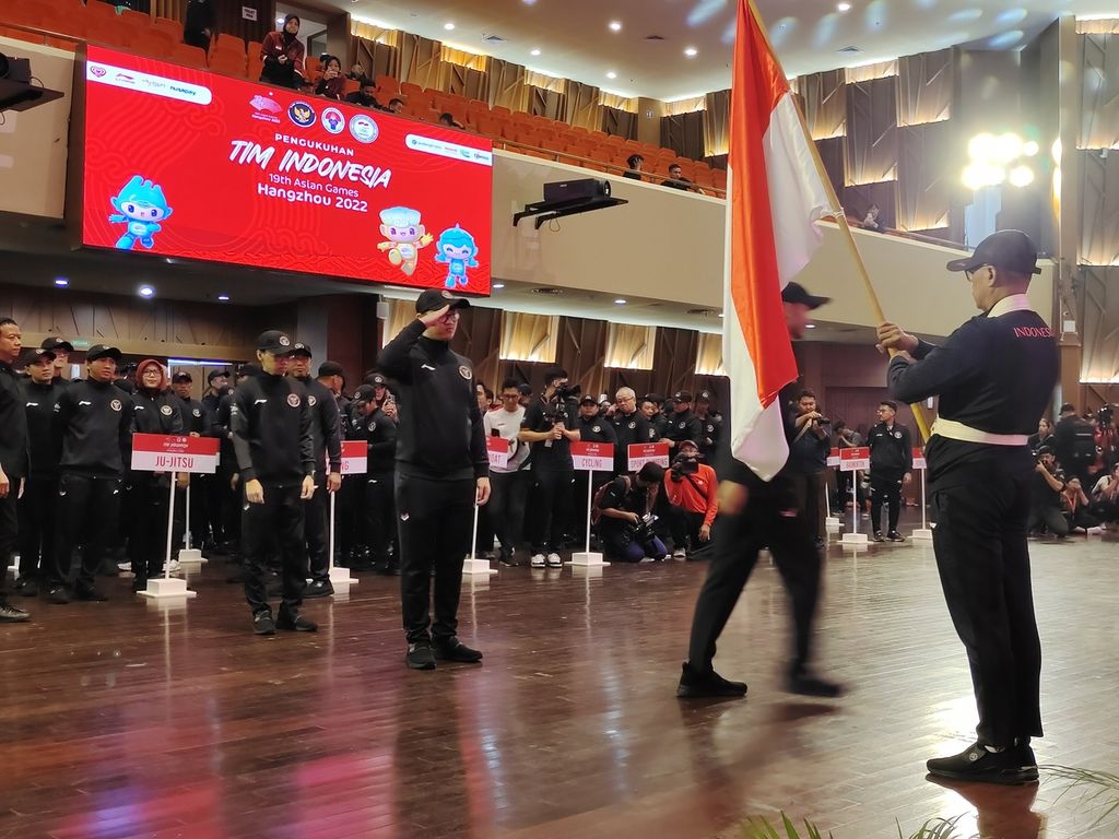 Atlet, pelatih, dan ofisial kontingen Indonesia untuk Asian Games Hangzhou, China 2022 mencium bendera seusai upacara pengukuhan kontingen di Kantor Kementerian Pekerjaan Umum dan Perumahan Rakyat, Jakarta, Selasa (19/9/2023). 