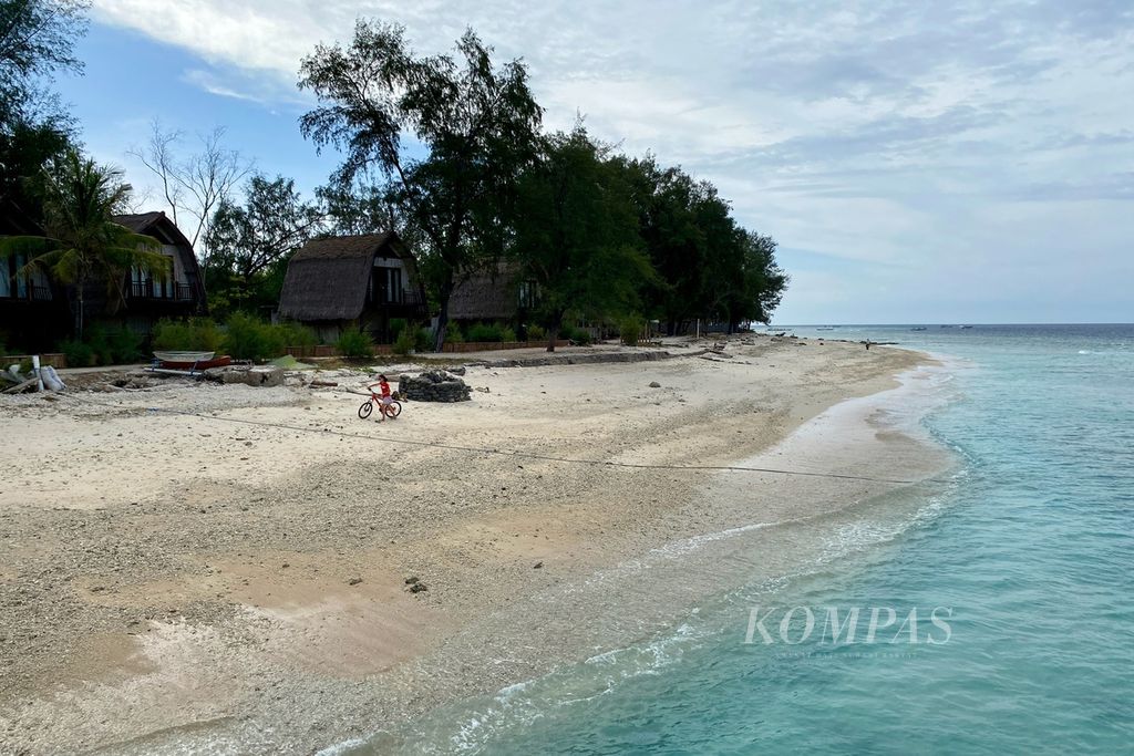 Wisatawan bersepeda di tepi pantai di Gili Meno di Desa Gili Indah, Kecamatan Pemenang, Kabupaten Lombok Utara, Nusa Tenggara Barat, Kamis (13/7/2023). Abrasi kian mengikis kawasan pesisir gili tersebut.