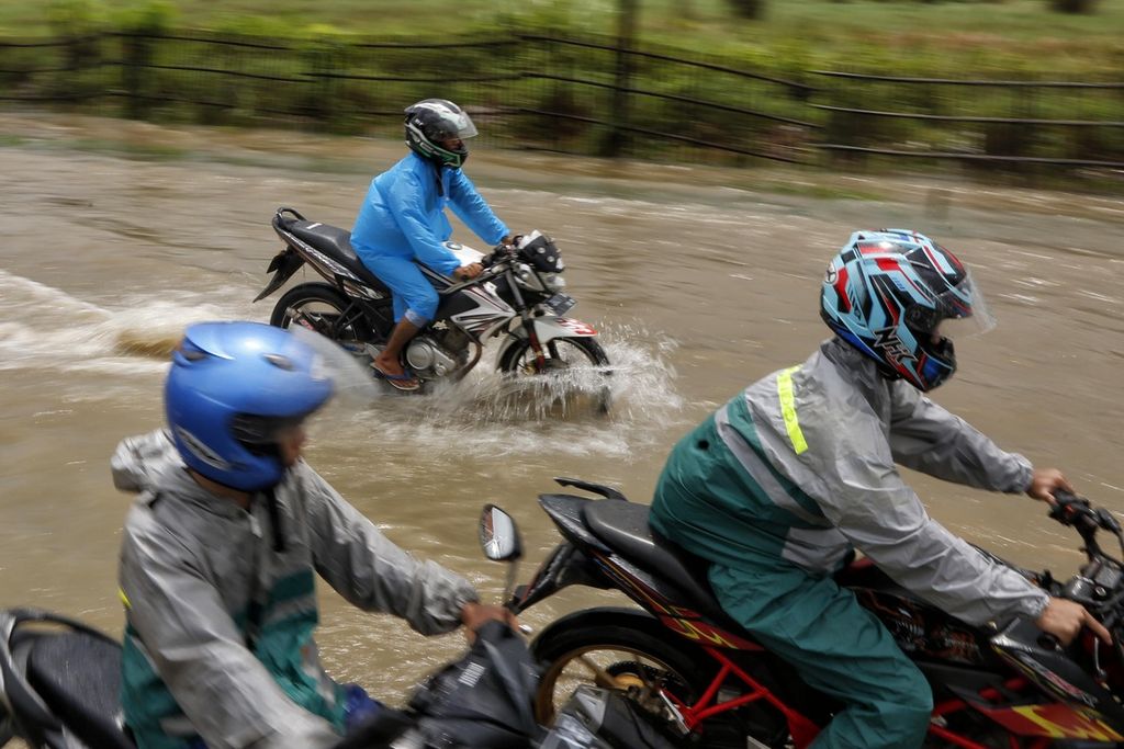 Motorcyclists try to cross the flood that inundated Jalan Pantura in the Kota Baru area, Karawang, West Java, Monday (27/2/2023).