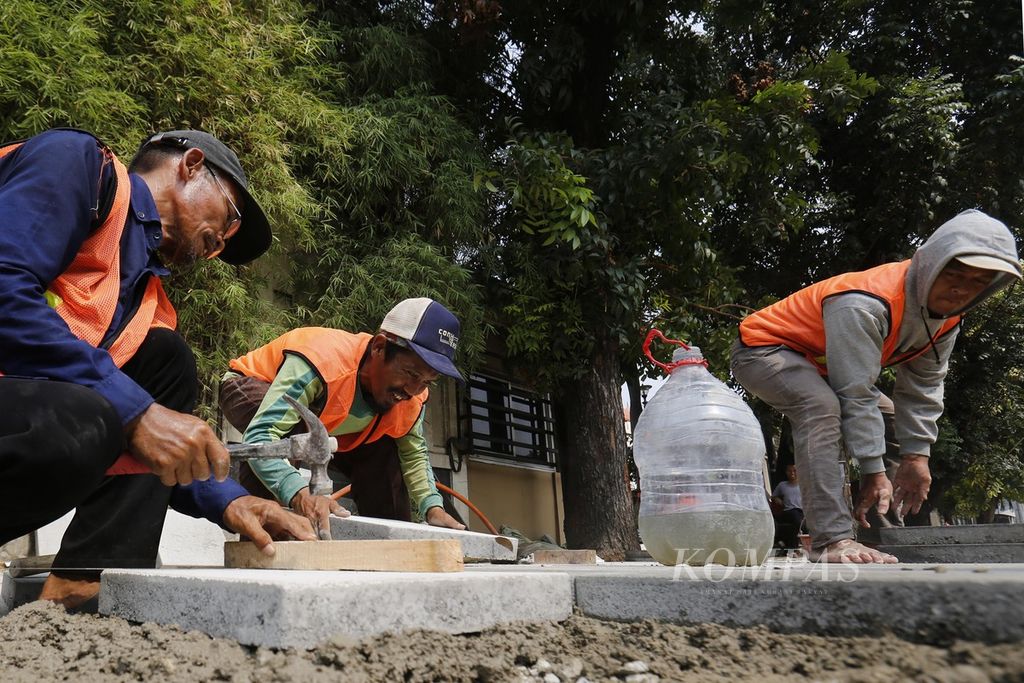 Pekerja menyelesaikan pembangunan trotoar di Jalan Matraman, Jakarta Timur, Rabu (1/11/2023). Pemprov DKI Jakarta membangun trotoar sepanjang 2,8 kilometer di Jalan Matraman untuk mendukung akses pejalan kaki ke <i>bus rapid transit</i> Koridor 5 dan KRL Stasiun Matraman. 