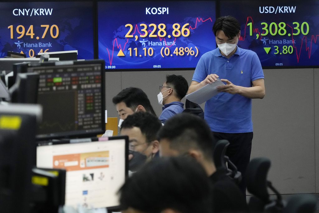 Seorang pedagang valuta asing di depan layar yang memperlihatkan Korea Composite Stock Price Index (KOSPI) dan nilai tukar mata uang Korea Selatan, won, di Seoul, 13 Juli 2022. 