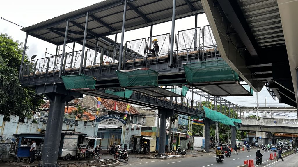 Penampakan petugas saat menyelesaikan pekerjaan Jembatan Penyeberangan Orang yang diintegrasikan antara Halte Matraman Baru dan Stasiun Matraman, Jakarta Timur, Selasa (27/12/2022).