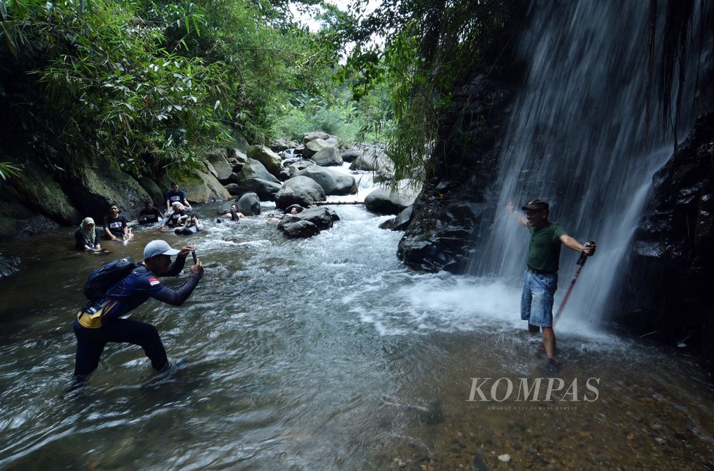 Para tamu peserta <i>trekking</i> menikmati air Curug Lewi Asih yang ada di salah satu jalur <i>trekking</i> di kawasan Sentul, Kecamatan Babakan Madang, Kabupaten Bogor, Jawa Barat, Sabtu (19/11/2022). 