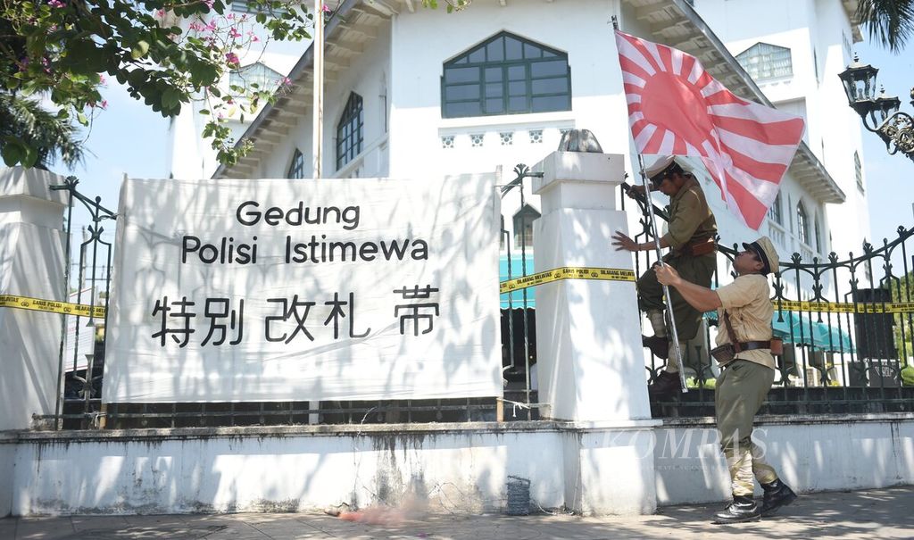 Fragmen penurunan bendera Jepang oleh agen polisi III Nainggolan dan Soegito saat teaterikal proklamasi Polisi Republik Indonesia dari Komunitas Roodebrug Soerabia di depan bekas Gedung Polisi Istimewa di Jalan Darmo, Surabaya, Senin (21/8/2023). 