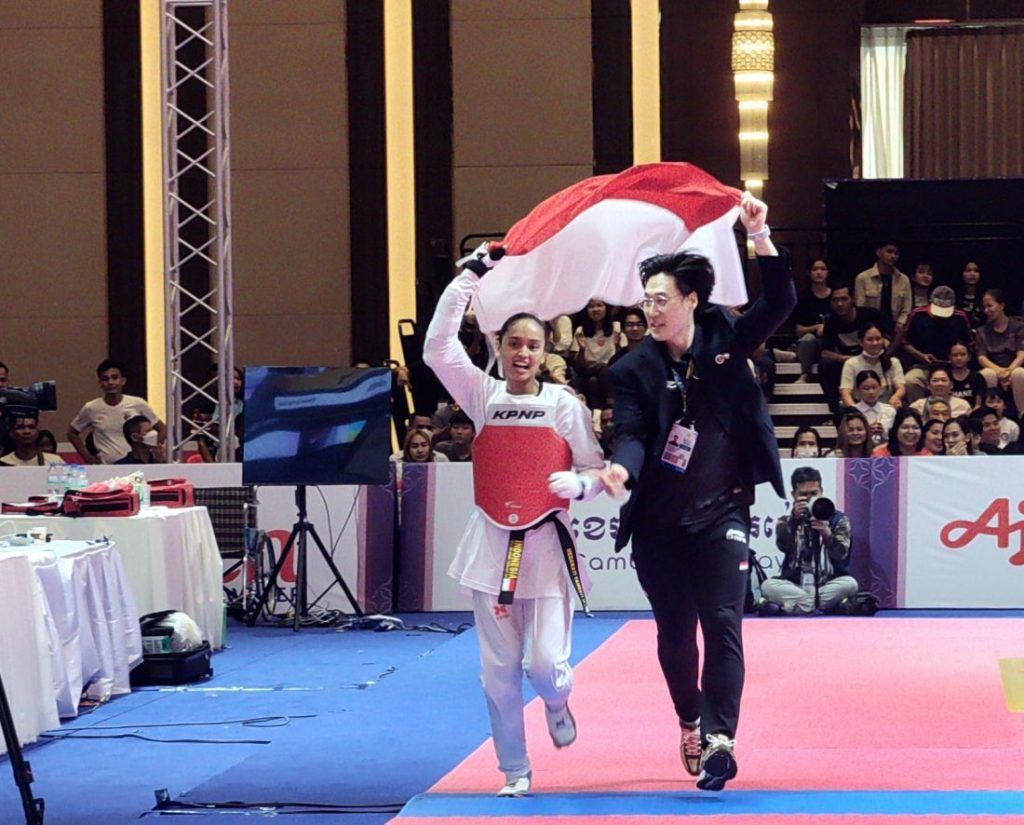 Atlet taekwondo Indonesia, Megawati Tamesti, mengibarkan bendera merah putih selepas memastikan meraih medali emas di SEA Games Kamboja 2023, Mei 2023. Megawati akan tampil di kualifikasi Asia untuk meraih tiket Olimpiade Paris 2024.