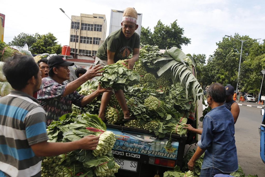 Buruh di Pasar Senen, Jakarta Pusat, membongkar sayur mayur yang didatangkan dengan angkutan bak terbuka dari Sukabumi, Senin (24/10/2022). 