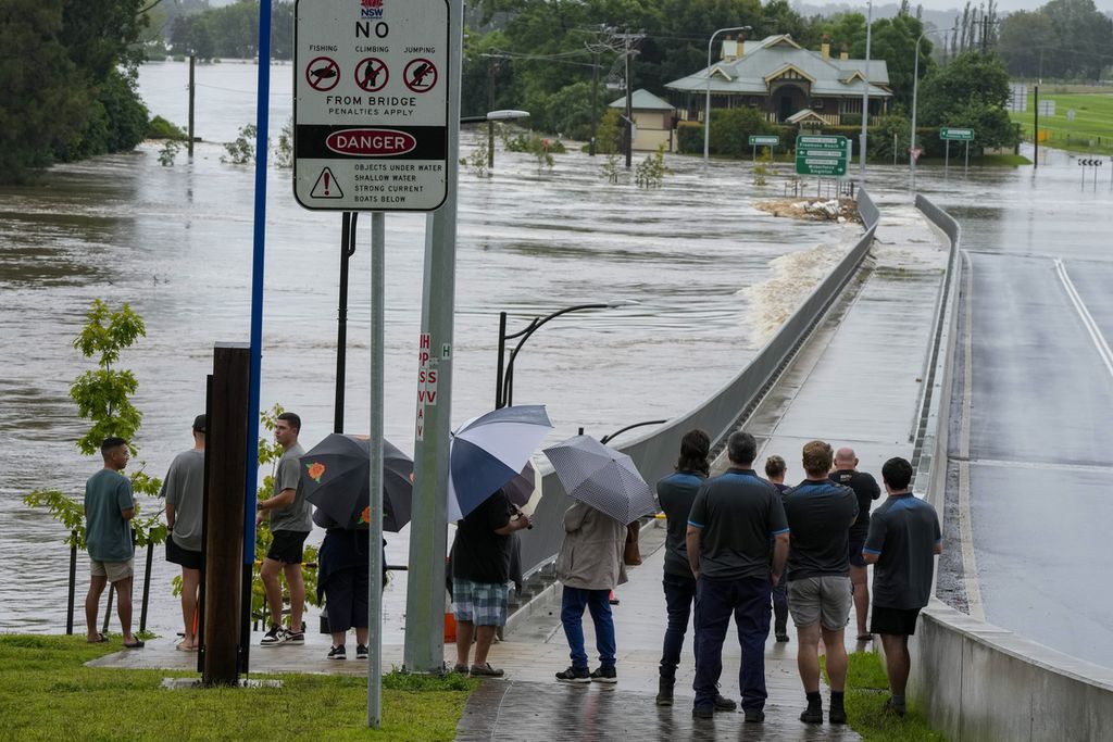 Warga berdiri di dekat Jembatan Windsor yang terendam banjir di pinggiran Sydney, Australia, Kamis (3/3/2022). Bencana akibat fenomena perubahan iklim menjadi tantangan bagi pemimpin Australia.