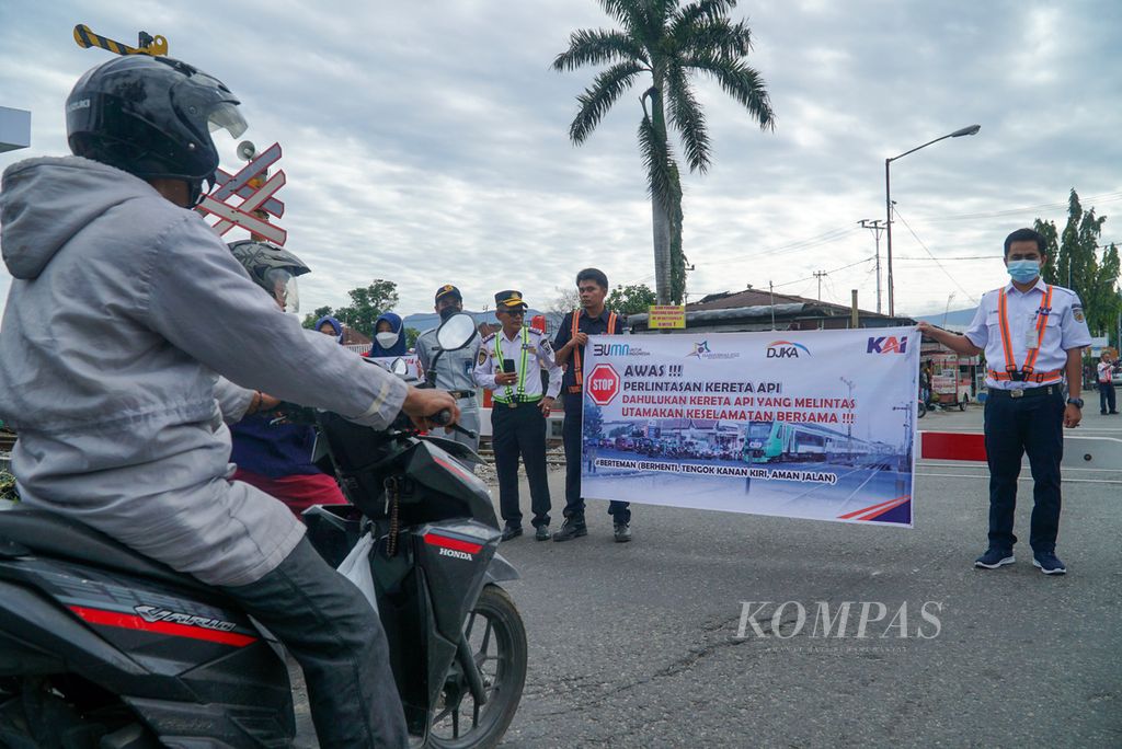 Petugas membentangkan spanduk imbauan kepada warga dalam kampanye keselamatan dalam rangka Hari Perhubungan Nasionla di perlintasan sebidang depan Stasiun Padang, Kecamatan Padang Timur, Kota Padang, Sumatera Barat, Sabtu (27/8/2022). 