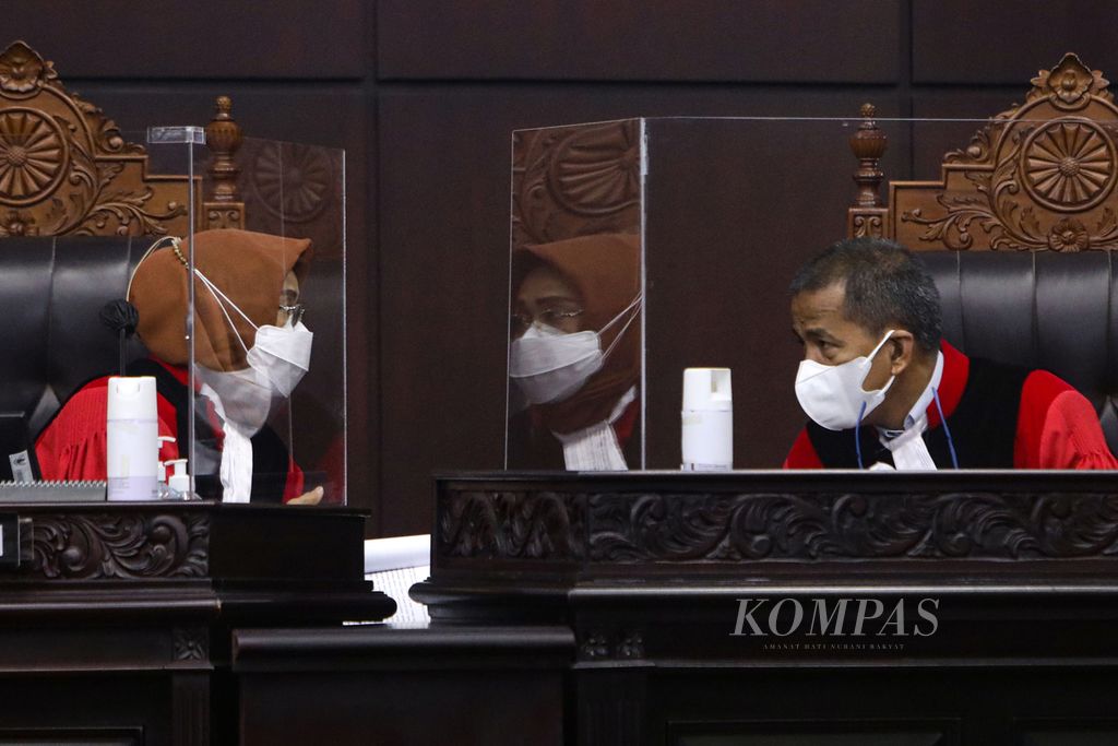 Hakim Mahkamah Konstitusi, Enny Nurbaningsih (kiri), berbincang dengan Saldi Isra saat mengikuti persidangan dengan agenda pembacaan putusan perkara di Gedung MK, Jakarta, Rabu (20/4/2022). 