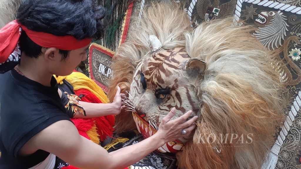 Wanto (23) menyunggi mahkota reog Ponorogo dalam acara karnaval Seabad NU, Selasa (7/2/2023), di Alun-alun Sidoarjo.