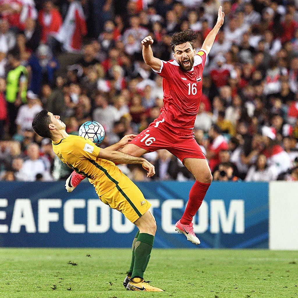 Pemain  Australia, Tomas Rogic (kiri), berebut bola dengan pemain Suriah,  Hamid Mido, pada laga kualifikasi Piala Dunia 2018 zona Asia  di  Sydney, Australia, Selasa (10/10). Australia memenangi laga dengan skor 2-1 lewat babak perpanjangan waktu.
