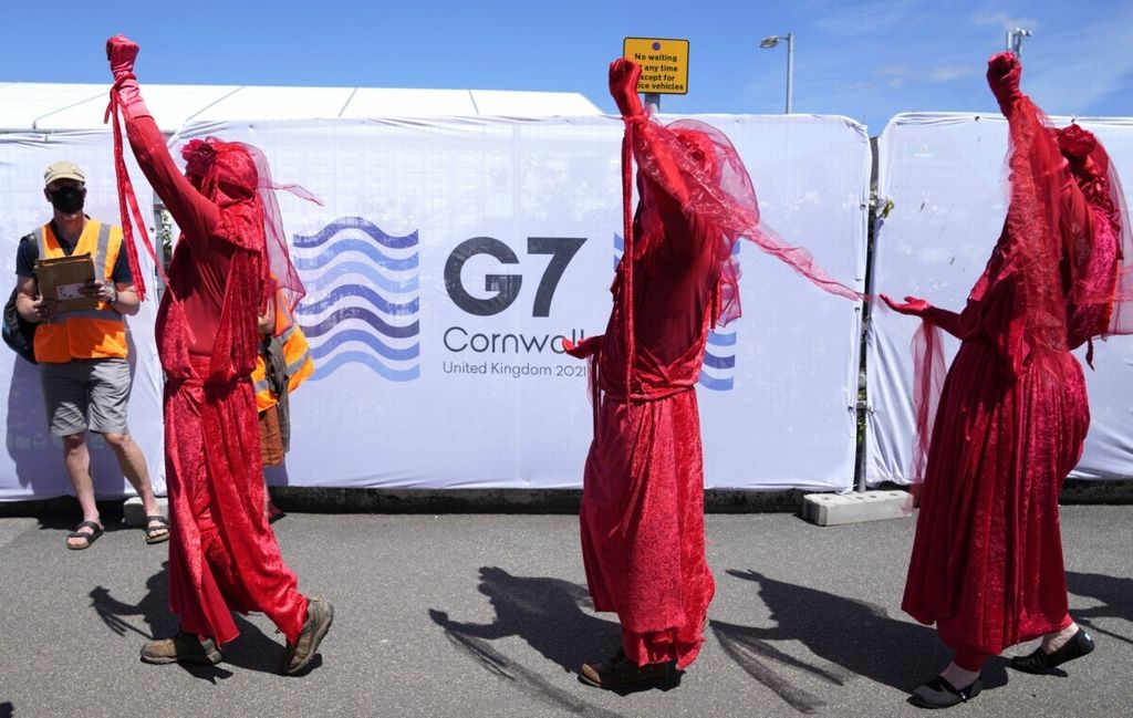 Aktivis berbaris dengan kostum berwarna merah saat demonstrasi di sekitar pertemuan G7 di Falmouth, Cornwall, Inggris, Sabtu, 12 Juni 2021.