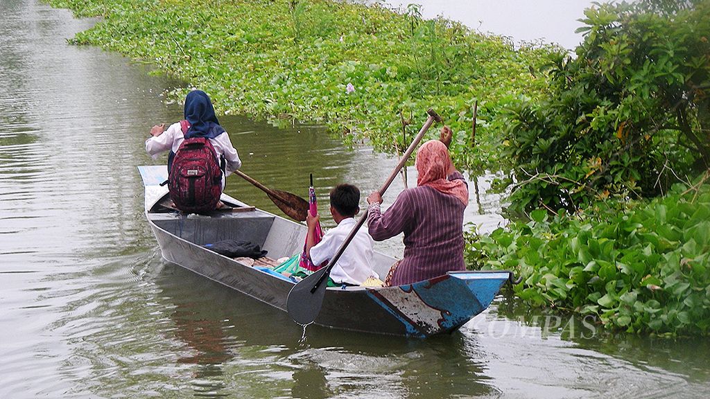 Selama banjir, para siswa di Desa Bojoasri, Kecamatan Kalitengah, Kabupaten Lamongan, Jawa Timur, diantar jemput orangtua dengan perahu. Sebagian siswa  memilih jalan kaki. Akses jalan menuju sekolah masih tergenang  sejak Sabtu pekan lalu hingga Senin (13/3) akibat  luapan Bengawan Jero.