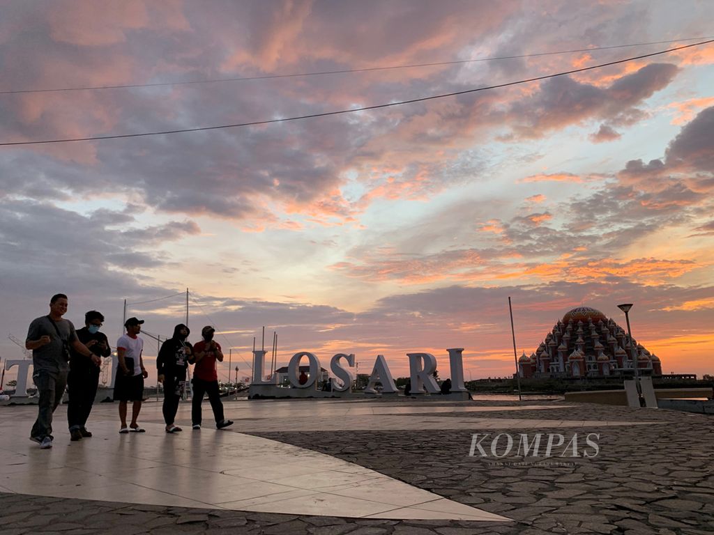 Pengunjung melintas di pelataran Anjungan Pantai Losari, Makassar, Rabu (30/9/2020) ditengah matahari yang sedang tenggelam. Ikon Makassar ini menjadi alternatif tempat bersantai bagi warga ditengah Pandemi Covid-19