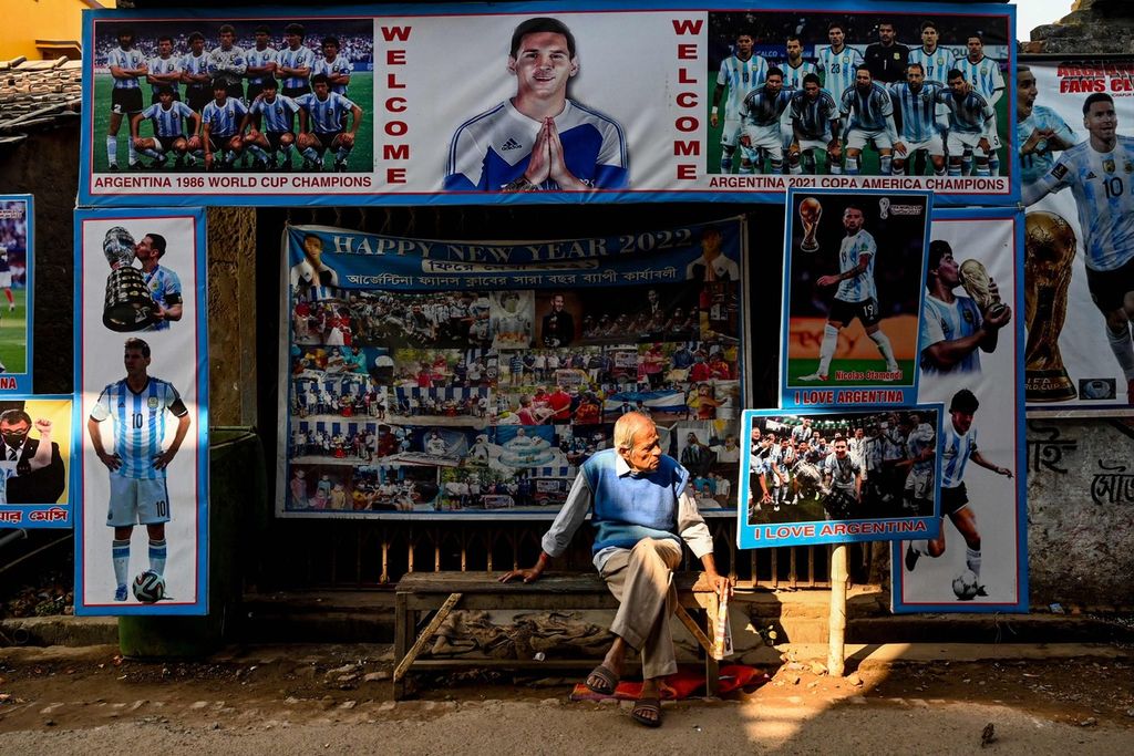 Seorang pria duduk di depan kedai teh yang didekorasi dengan poster tim nasional Argentina di Ichhapur, sekitar 35 kilometer dari Kolkata, India, Senin (12/12/2022). 