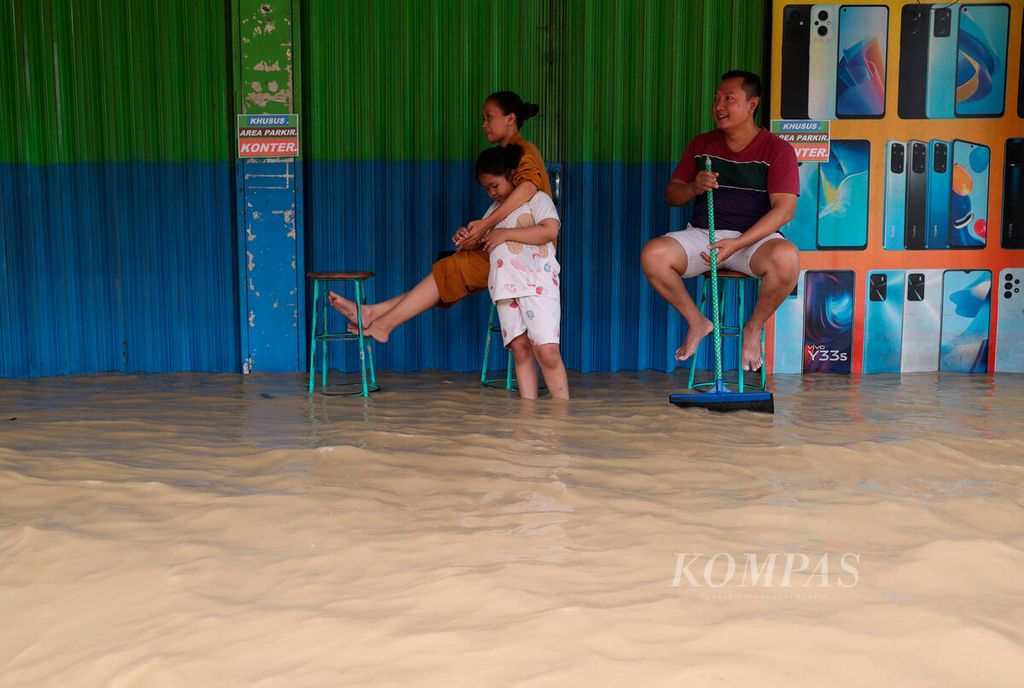 Pemilik toko berada di depan tempat usahanya yang tergenang banjir di Desa Gubug, Kecamatan Gubug, Kabupaten Grobogan, Jawa Tengah, Selasa (6/2/2024). 