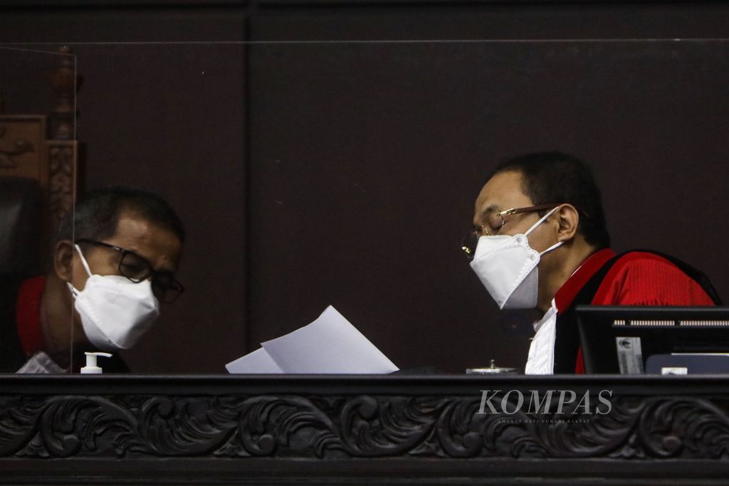 Hakim konsitusi Saldi Isra (kiri) berbincang dengan hakim konstitusi Suhartoyo saat pembacaan keputusan terkait perkara perselisihan sengketa Pemilihan Kepala Daerah 2020 di Gedung Mahkamah Konstitusi, Jakarta, Senin (15/2/2021).
