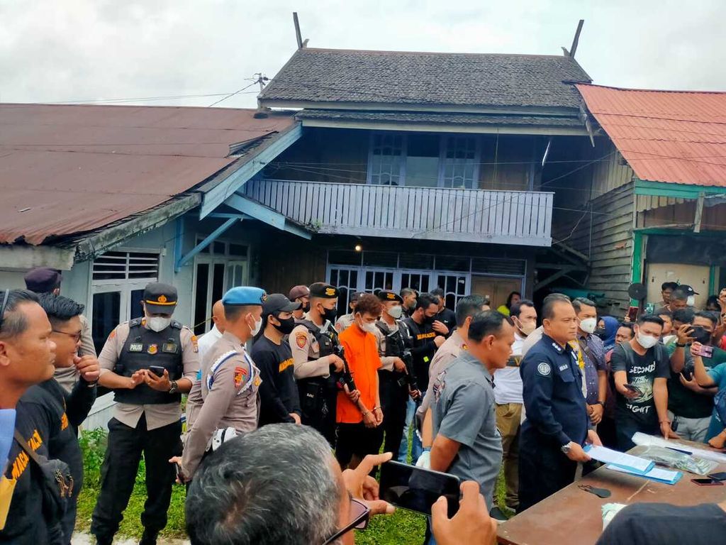 Pelaku F (30) mengenakan baju tahanan saat melakukan prarekosntruksi di rumah korban di Jalan Cempaka, Kota Palangkaraya, Kalimantan Tengah, Minggu (9/10/2022). Pelaku dijaga ketat aparat karena banyak keluarga korban yang datang.