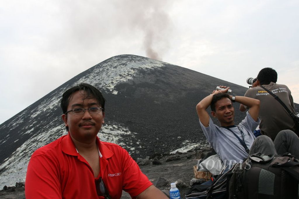 Wartawan <i>Kompas</i>, Wisnu Aji Dewabrata (kiri) dan Yulvianus Harjono (tengah), dengan latar belakang Gunung Anak Krakatau yang mengeluarkan asap, Minggu (25/7/2010).