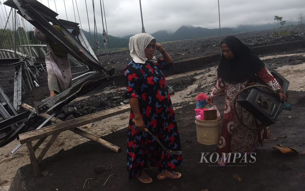 Warga melewati jembatan gantung yang rusak akibat terjangan banjir lahar hujan Gunung Semeru di Dusun Bondeli Selatan, Desa Sumberwuluh, Kecamatan Candipuro, Lumajang, Jatim, Sabtu (8/7/2023). Akibat cuaca ekstrem di Lumajang membuat enam jembatan putus akibat banjir limpasan lahar hujan Gunung Semeru. 