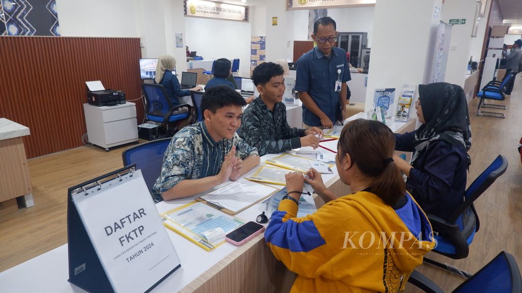 Petugas melayani warga yang mengurus perubahan fasilitas kesehatan tingkat pertama (FKTP) di konter layanan BPJS Kesehatan di Mal Pelayanan Publik (MPP) ”Baiman” Kota Banjarmasin, Kalimantan Selatan, Kamis (25/7/2024). 