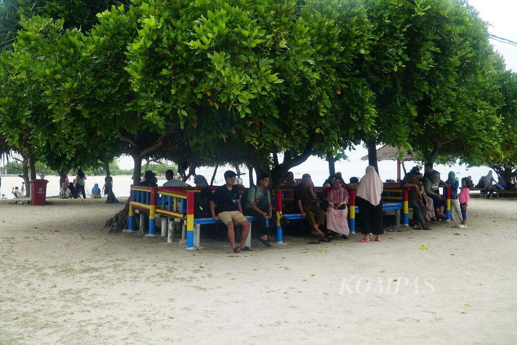 Wisatawan duduk menikmati suasana Pantai Pasir Perawan di Pulau Pari, Kabupaten Administrasi Kepulauan Seribu, Jakarta, Senin (1/1/2024). 