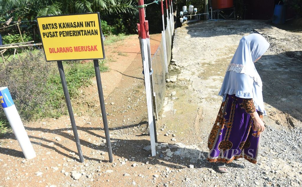 Raniah (57) berada di samping papan peringatan batas inti pusat pemerintahan di sebelah halaman rumahnya di Desa Bumi Harapan, Kecamatan Sepaku, Kabupaten Penajam Paser Utara, Kalimantan Timur, Selasa (26/7/2022). 