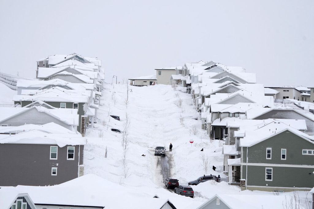 Kendaraan melintasi kawasan permukiman yang tertutup salju di Draper, Utah, AS, Rabu (22/2/2023). 