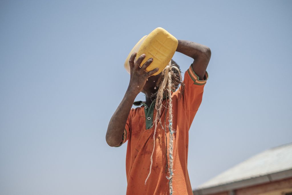 Seorang anak meminum air dari sebuah tempat air di sela-sela pembagian makanan oleh Badan Pangan Dunia di Adiale, Gode, Ethiopia pada 6 April 2022. Negara-negara di Afrika mengalami tingkat kelaparan tinggi warganya antara lain akibat gagal panen dan pemrosesan panenan yang buruk. 