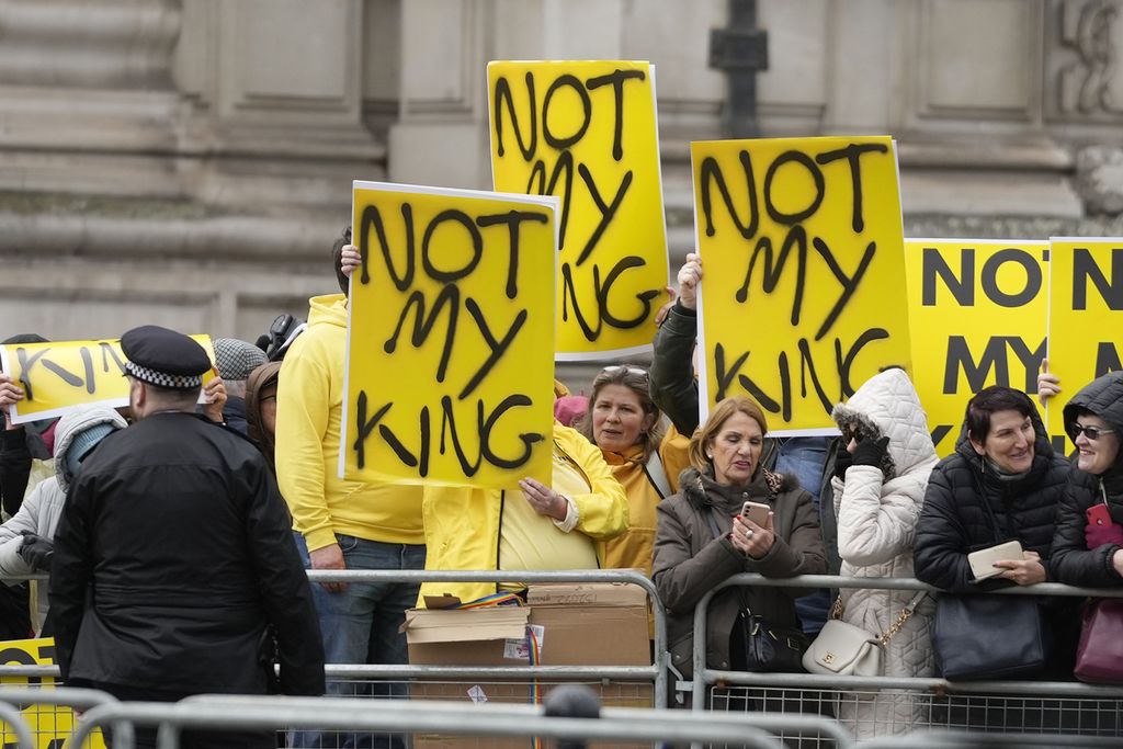 Para pengunjuk rasa memegang plakat dengan pesan ”Bukan Rajaku” sebelum Raja Inggris Charles III tiba untuk menghadiri kebaktian tahunan Hari Persemakmuran di Westminster Abbey di London, Senin, 13 Maret 2023. 