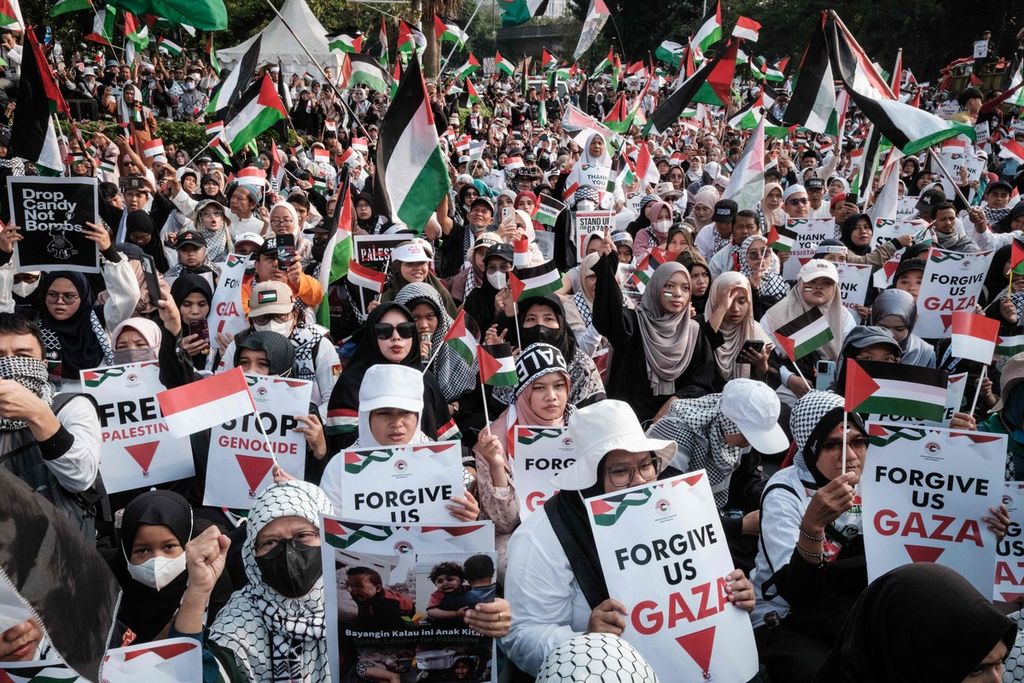 Para pengunjuk rasa mengibarkan bendera Palestina dan memperlihatkan poster berisi dukungan kepada Palestina dalam unjuk rasa di Jakarta, Minggu (6/10/2024). 