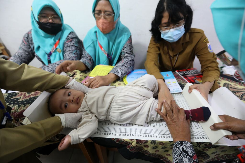 Kader posyandu menimbang berat badan seorang bayi saat berkunjung ke pelayanan posyandu di RW 005 Rawa Terate, Cakung, Jakarta Timur, Selasa (14/2/2023). Pengukuran tinggi badan anak dilakukan untuk memonitor pertumbuhan anak. 
