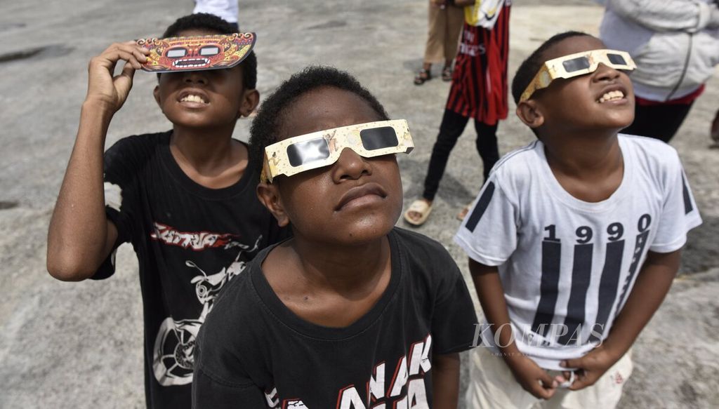 Dengan memakai kacamata matahari, anak-anak antusias menyaksikan fase demi fase gerhana Matahari total dari lokasi pengamatan di Pelabuhan BMJ, Biak, Papua, Kamis (20/4/2023). 