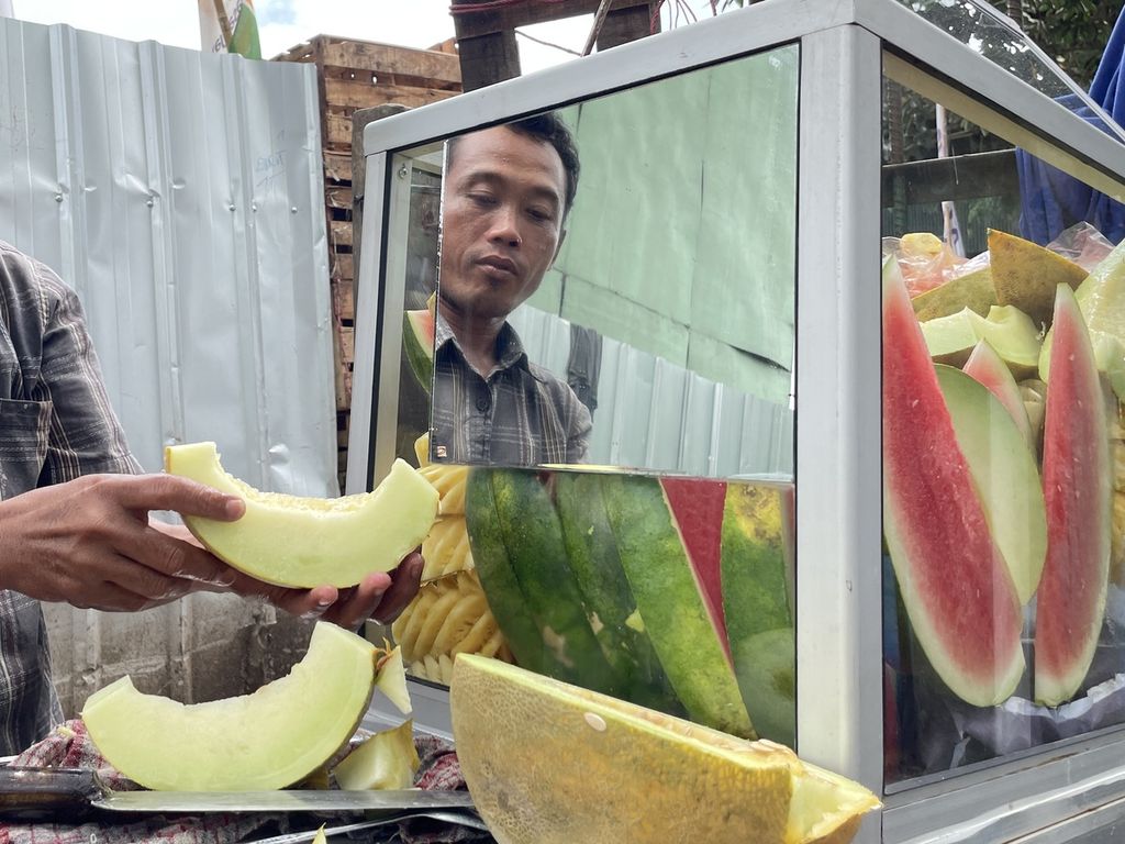Kelir (32) sedang menata buah di gerobak pada Jumat (17/2/2023) di Pasar Kramatjati, sebelum menjajakan dagangan buah dan rujaknya di sekitar Jakarta Timur.