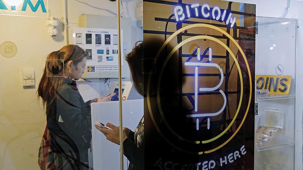 Warga  menggunakan anjungan transaksi mandiri (ATM) bitcoin di Hong Kong, 8 Desember lalu.  Bitcoin adalah mata uang virtual  paling populer di dunia. Mata uang ini tidak terikat dengan bank atau pemerintah dan memungkinkan penggunanya membelanjakan uang secara anonim. Setiap kali mata uang virtual itu diperdagangkan, umumnya ada deretan kode komputer yang secara digital harus dimasukkan. 