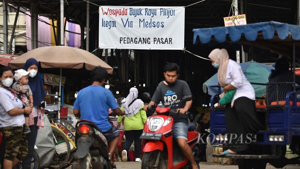 Spanduk ajakan untuk mewaspadai praktik pinjaman daring ilegal menghiasi pintu masuk Pasar Muara Angke, Penjaringan, Jakarta Utara, Minggu (14/11/2021). 