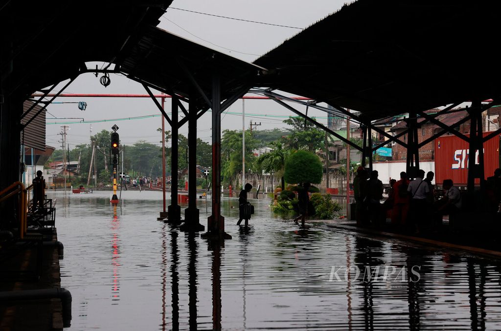Penumpang kereta api berjalan melintasi banjir yang menggenangi Stasiun Tawang, Kota Semarang, Jawa Tengah, Kamis (14/3/2024). Cuaca buruk dalam beberapa hari ini menyebabkan banjir sehingga melumpuhkan fasilitas publik dan menggenangi permukiman warga. Banjir juga memutus akses utama jalur pantura sehingga menyebabkan kemacetan panjang hingga dua hari ini. 