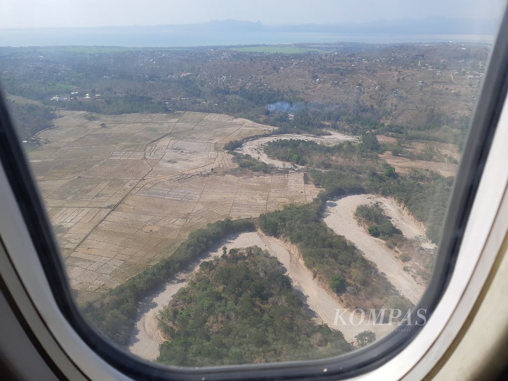 Kekeringan di wilayah Kabupaten Kupang, Nusa Tenggara Timur, sebagaimana dipotret dari jendela pesawat udara pada Jumat (29/9/2023). Aliran sungai di daerah itu mengering. Banyak sawah ditinggalkan. Beberapa lahan pertanian yang masih diolah mengandalkan air dari sumur.