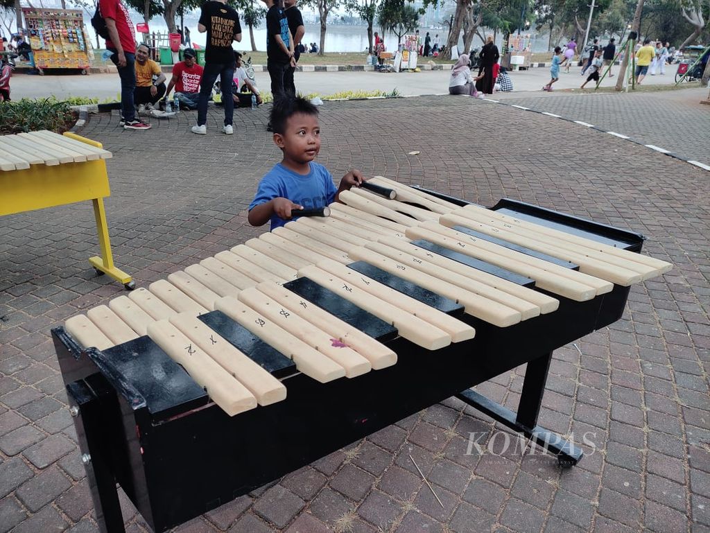 Seorang anak mencoba bermain kolintang di Waduk Pluit, Jakarta, Minggu (10/9/2023).