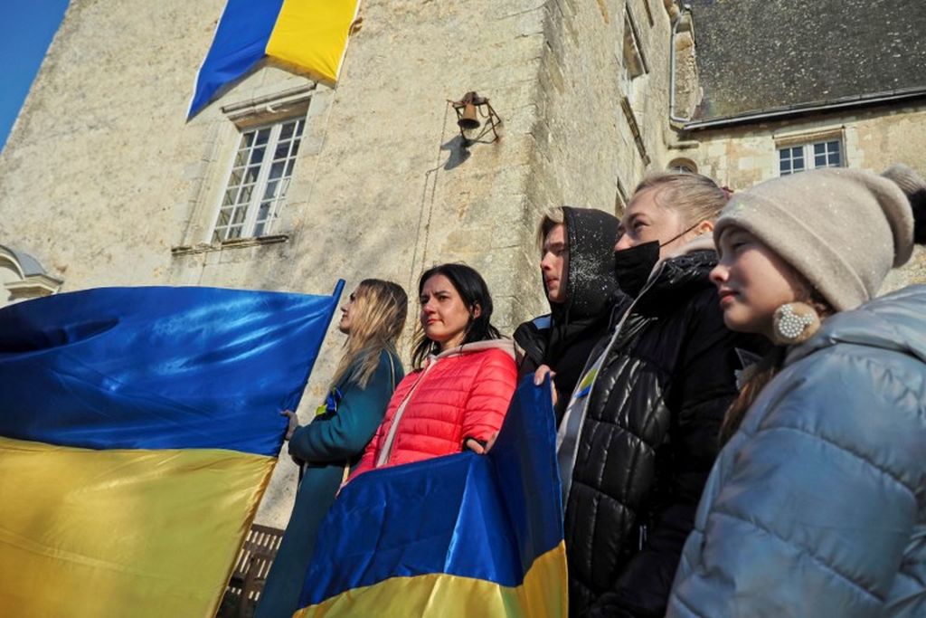 Anastasia (kedua dari kiri) dan Natalia (kedua dari kanan), dua ibu Ukraina dengan anak-anak mereka, memegang bendera Ukraina saat disambut di Chateau de Sache, dekat Tours, Perancis tengah, 7 Maret 2022. 