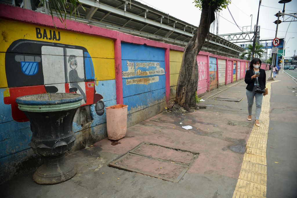 Seorang warga melintas di samping mural bergambar bajaj di sekitar Stasiun Jatinegara, Jakarta Timur, Rabu (18/1/2023).