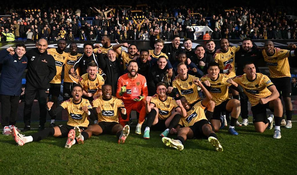 Kiper Maidstone United, Lucas Covolan (tengah), berpose bersama rekan-rekannya seusai memenangi laga Piala FA lawan Ipswich Town, 2-1, di Portman Road, Ipswich, Sabtu (27/1/2024). Tim nonliga Maidstone membuat kejutan dengan menyingkirkan tim divisi Championship, Ipswich.