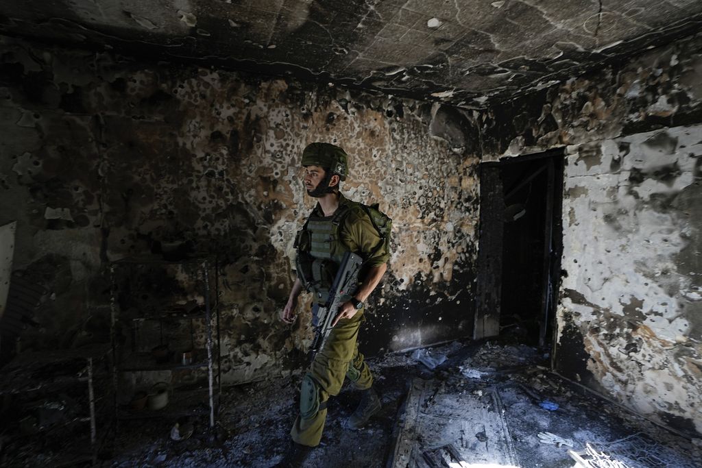 Seorang tentara Israel memeriksa sebuah rumah yang rusak akibat serangan Kelompok Hamas di Kibbutz Kfar Azza, Israel, Rabu (18/10/2023). 